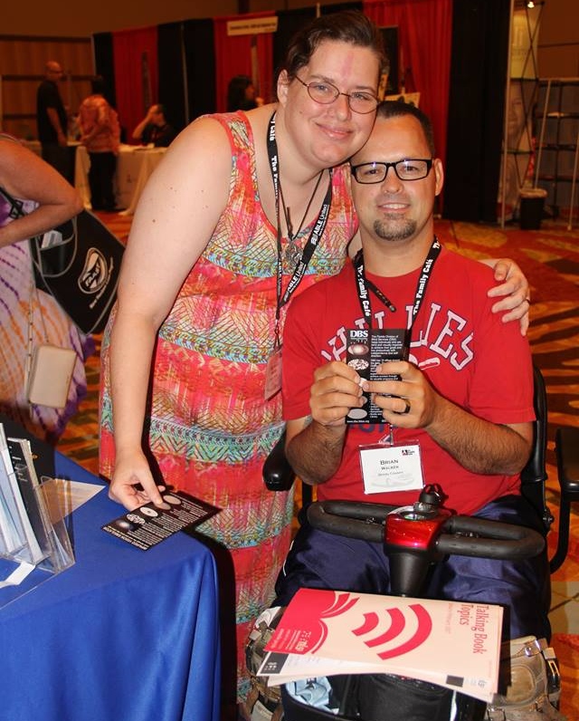 Brian and Michelle Walker hugging one another next to the DBS exhibit table.